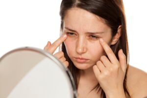 Woman examining her eyes in the mirror